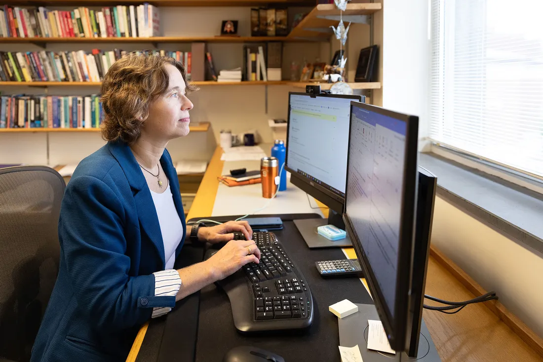 A professor typing at a double monitor