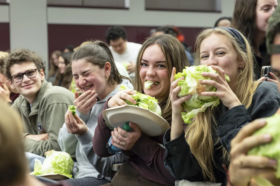 Students smiling and eating heads of lettuce for the Lettuce Club's annual fundraising contest.