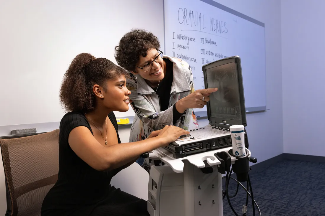 Student and teaching working on computer.