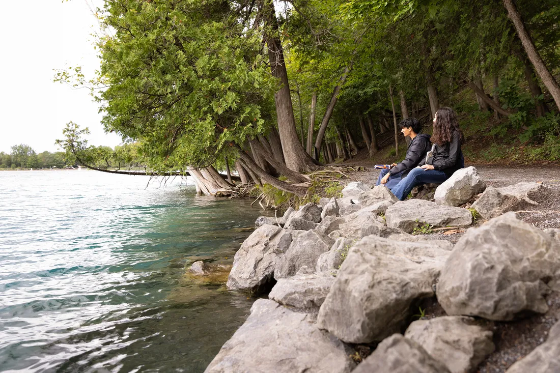 People sitting on rocks by a lake.