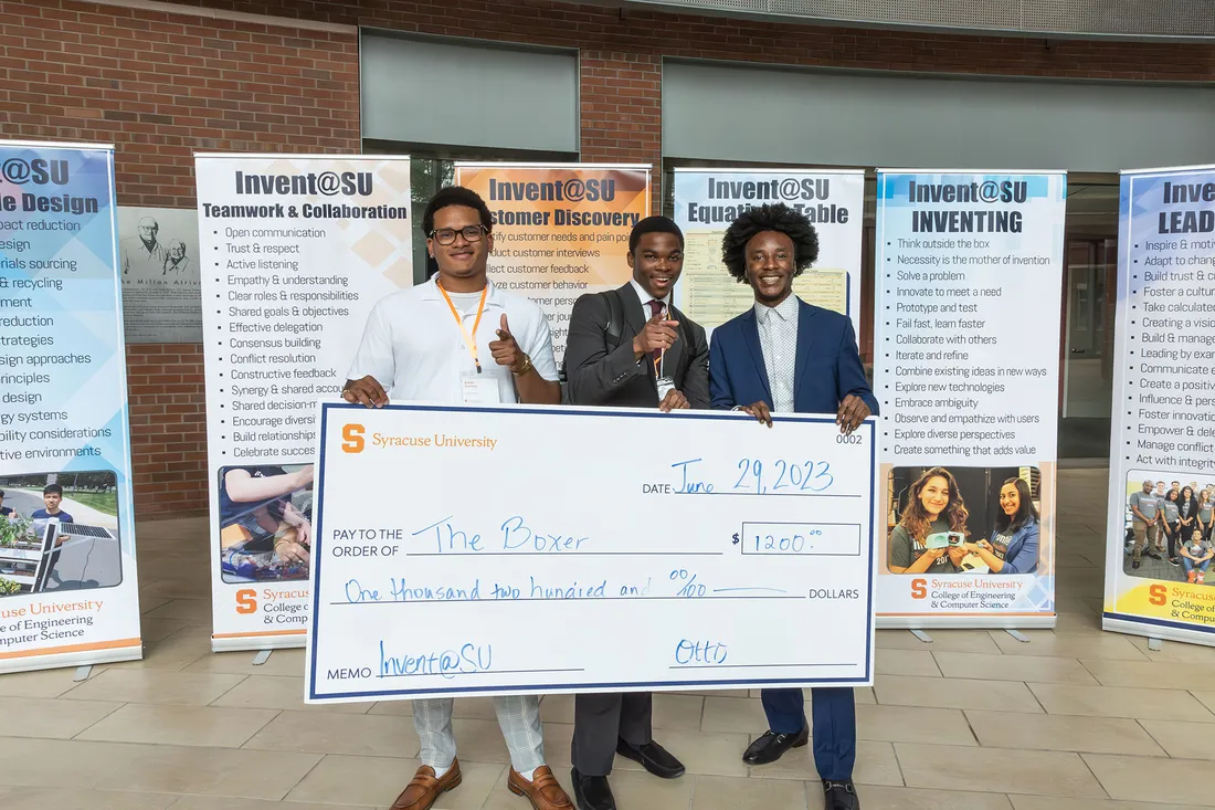 Three students holding large prize money check.