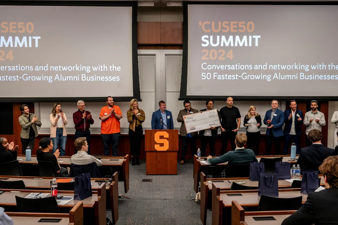 People standing in front of presentation screens at the CUSE 50 Summit 2024.