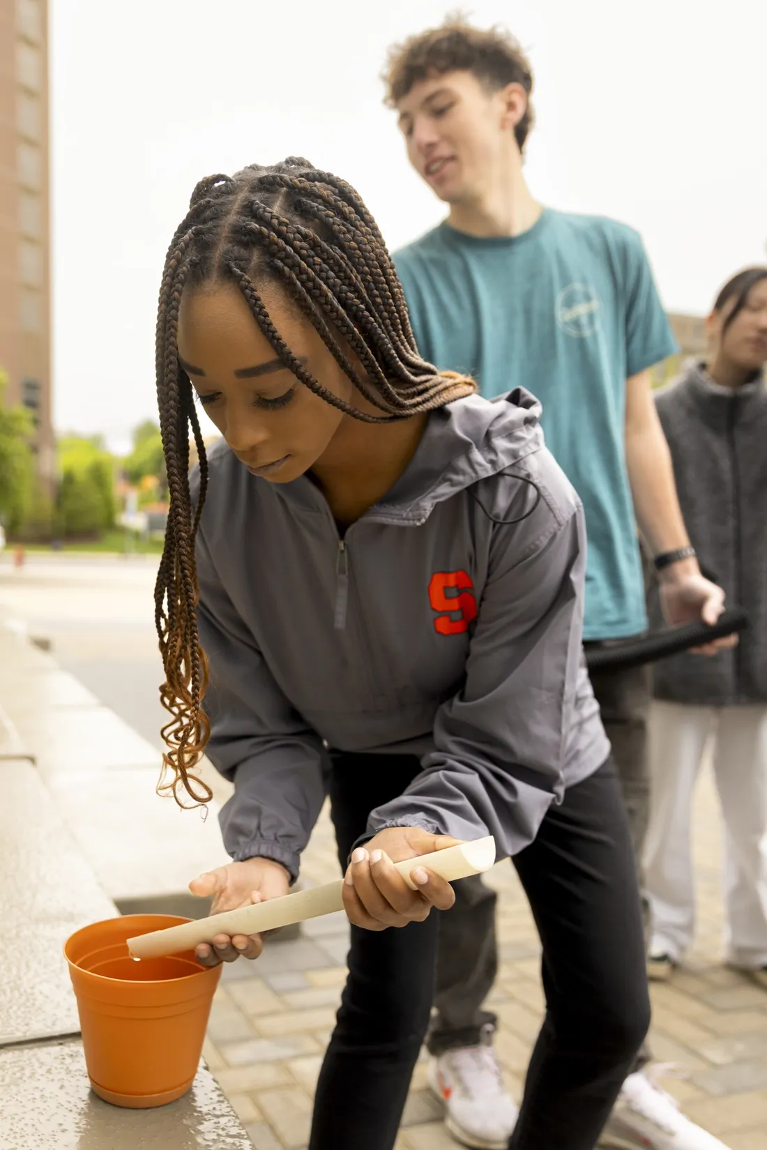 Student pouring water into a bucket.