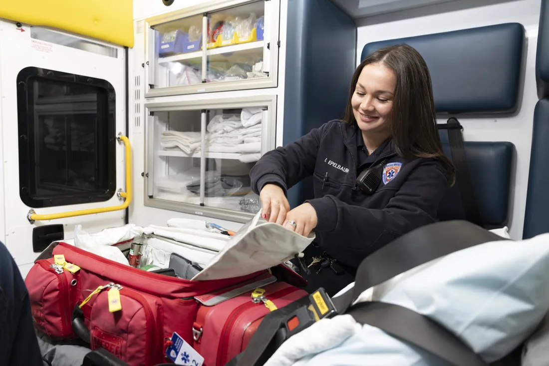 Person inside ambulance organizing medical gear.