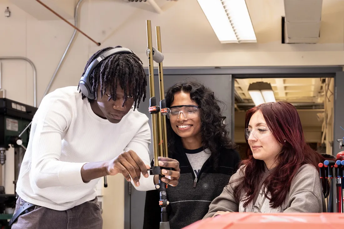 Three students test devices in lab.