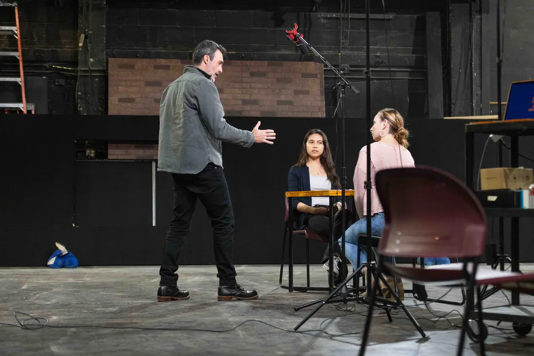 Alumni Reid Scott standing on a stage with students.