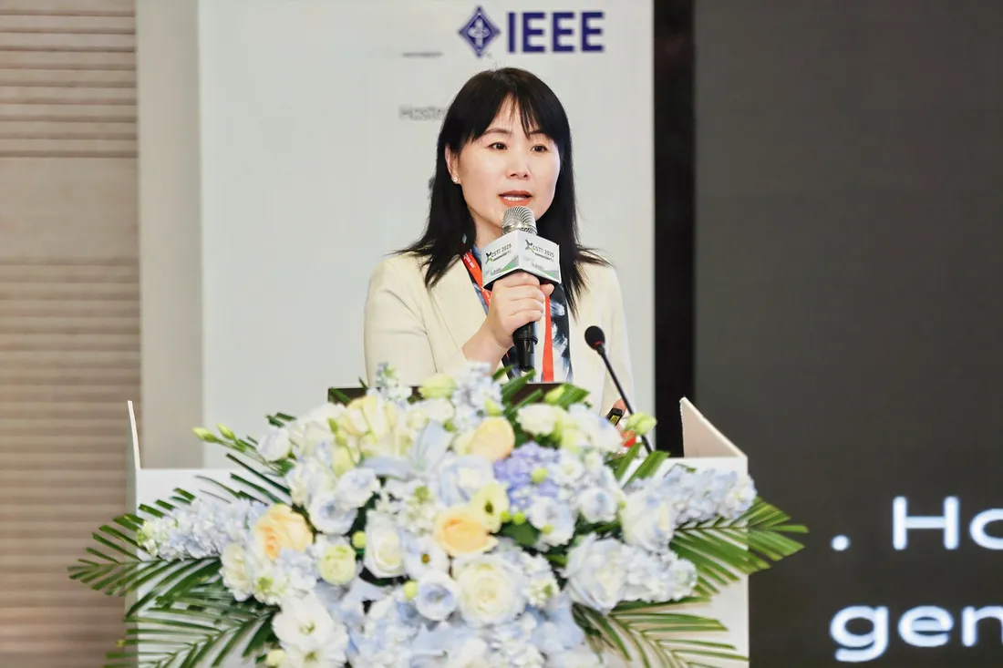 Person standing a podium with flowers speaking with a microphone in hand.