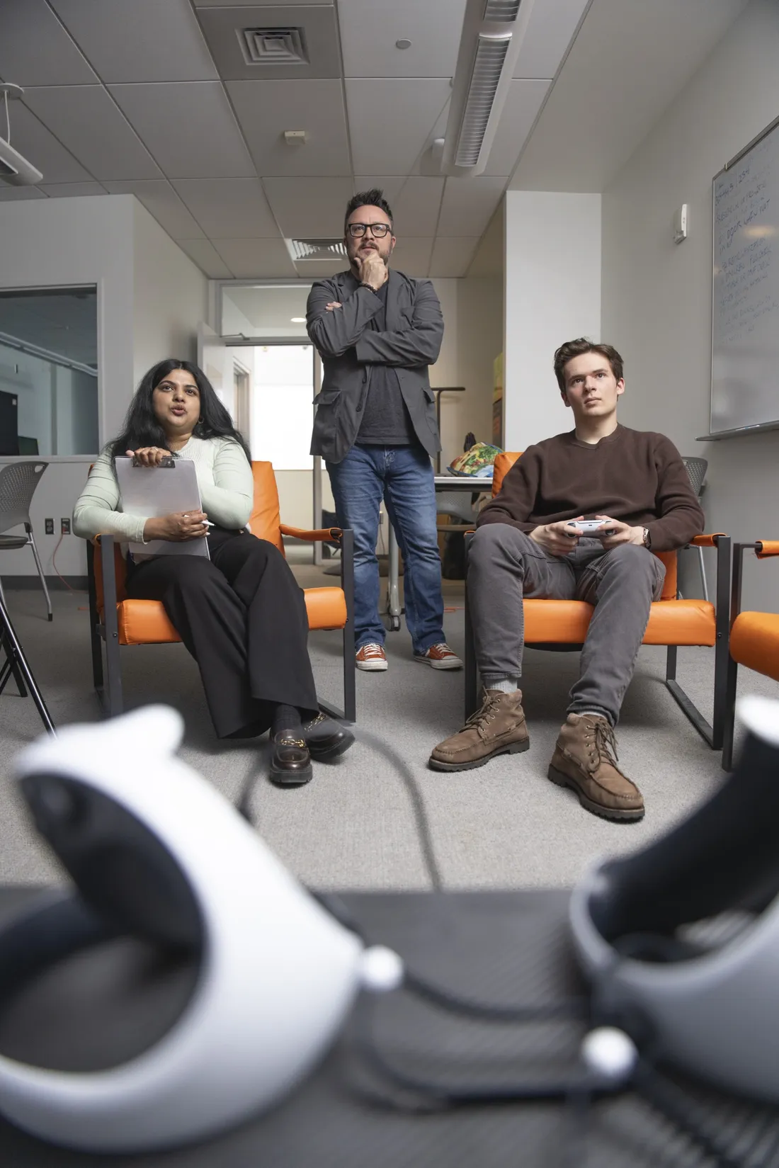 Professor Nick Bowman standing with two students who are playing a video game.