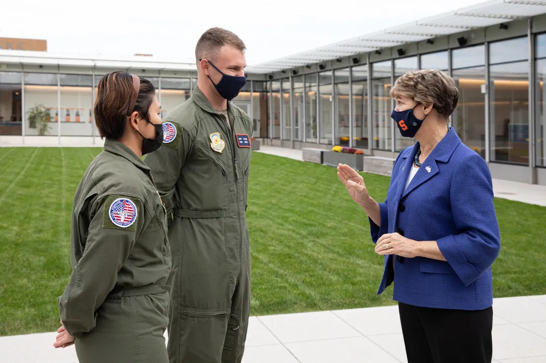 Eileen Collins standing outside in conversation with two people in military uniforms.
