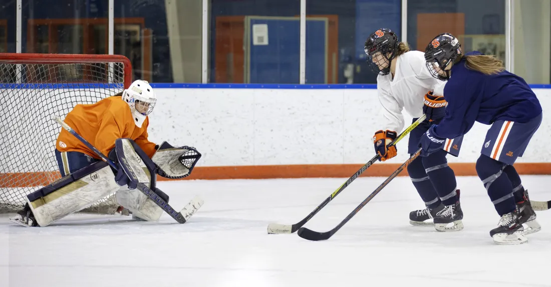Athletes on the women's club ice hockey team attempting to score a goal.