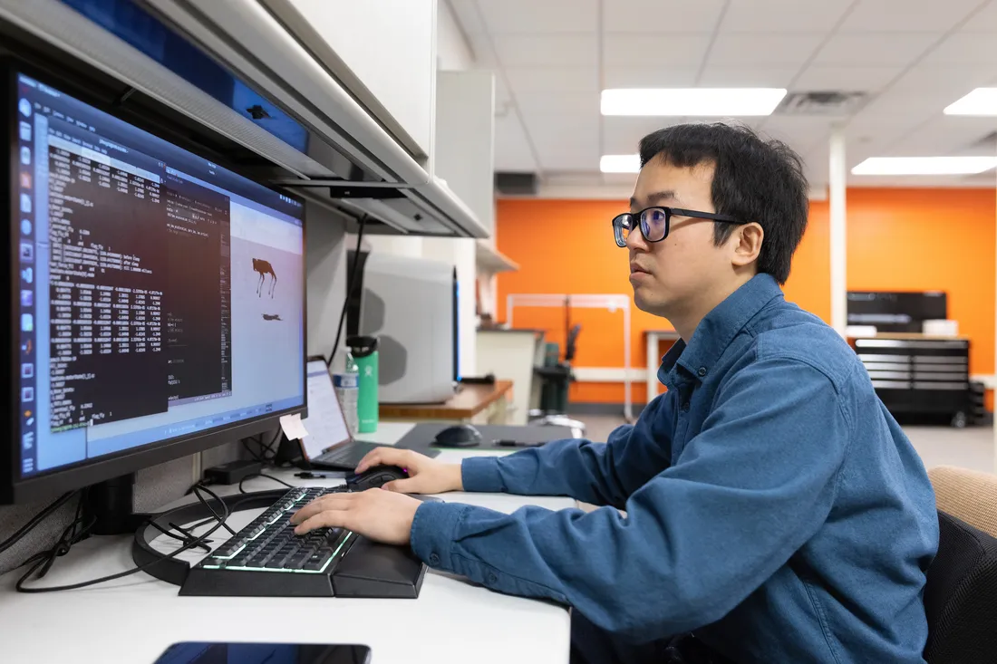 Medium shot of Jing Cheng designing a control scheme on the computer.