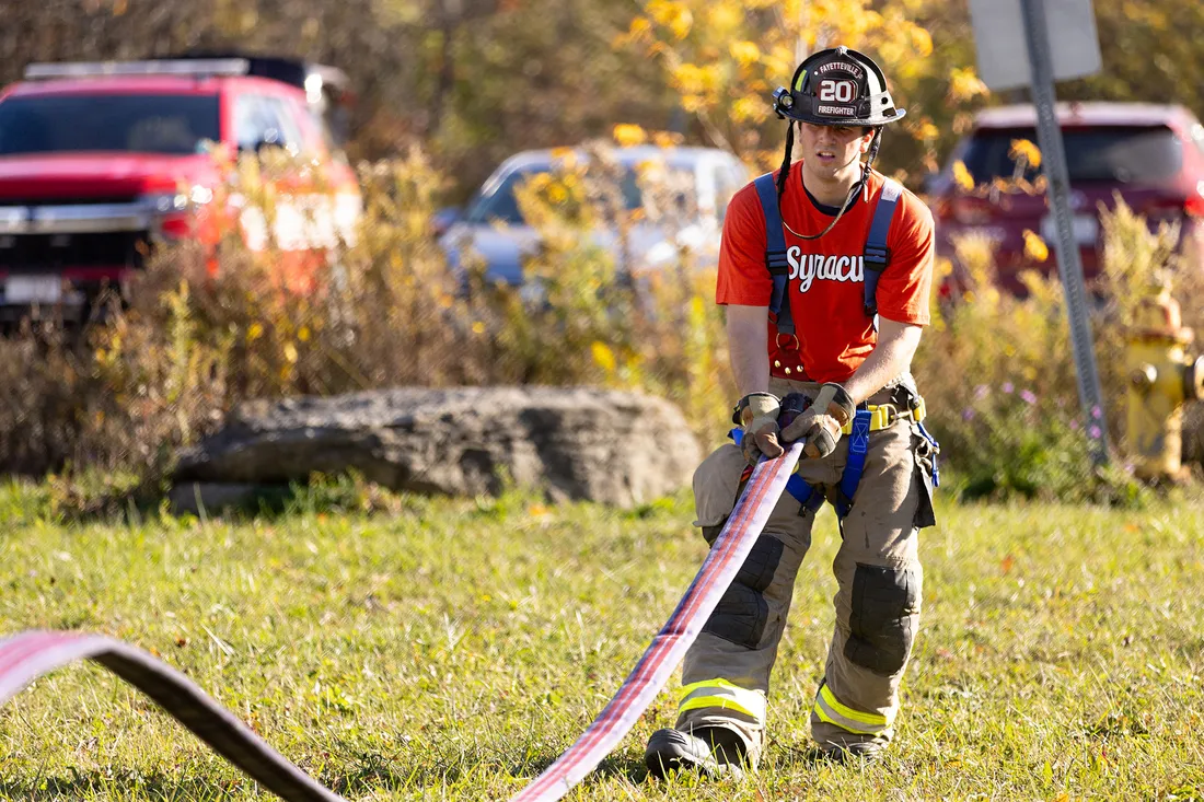 Ryan Derkowski pulling a fire hose.