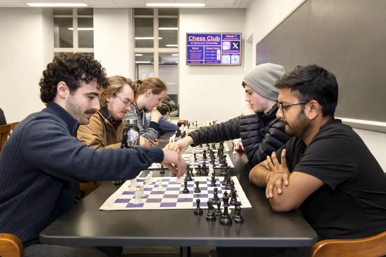 Students sitting at a table playing chess.