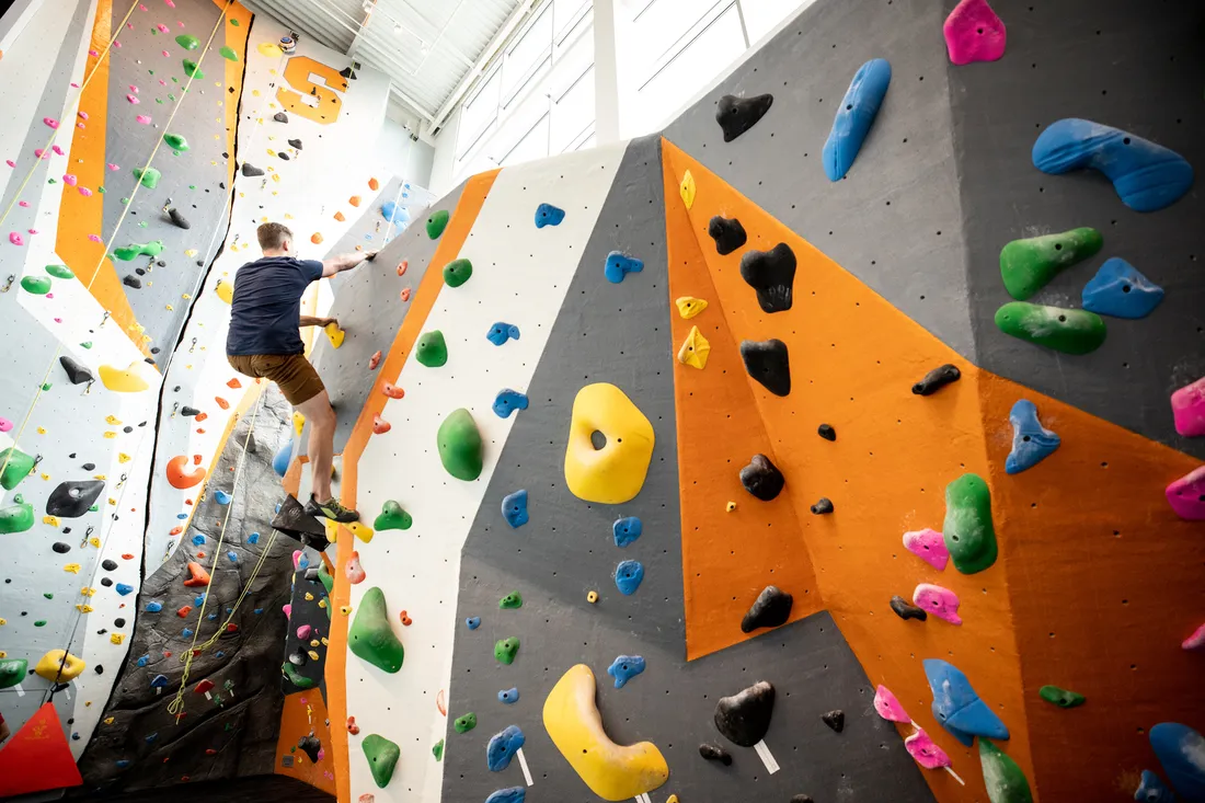 Student climbs rock wall inside of the Barnes Center at The Arch.