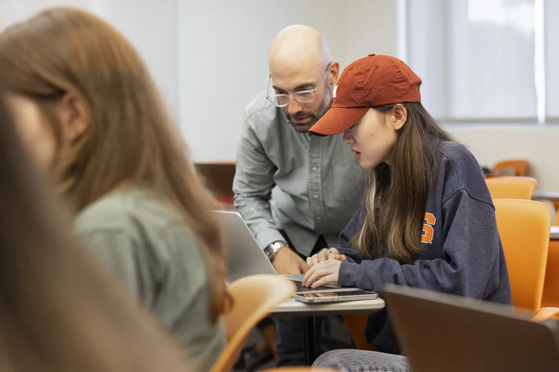 Professor standing next to student helping them with work.