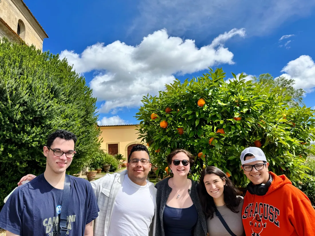 Bella Cecchinelli '29 and their classmates standing in front of an orange tree in Italy.