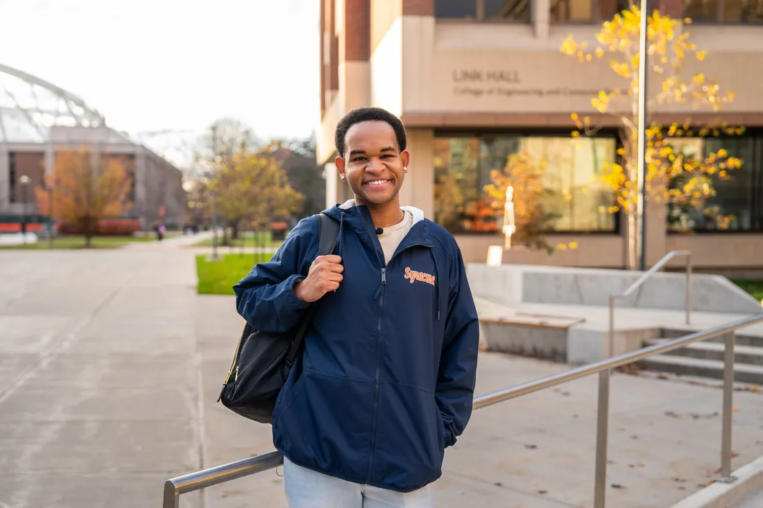 A student standing outside and smiling.