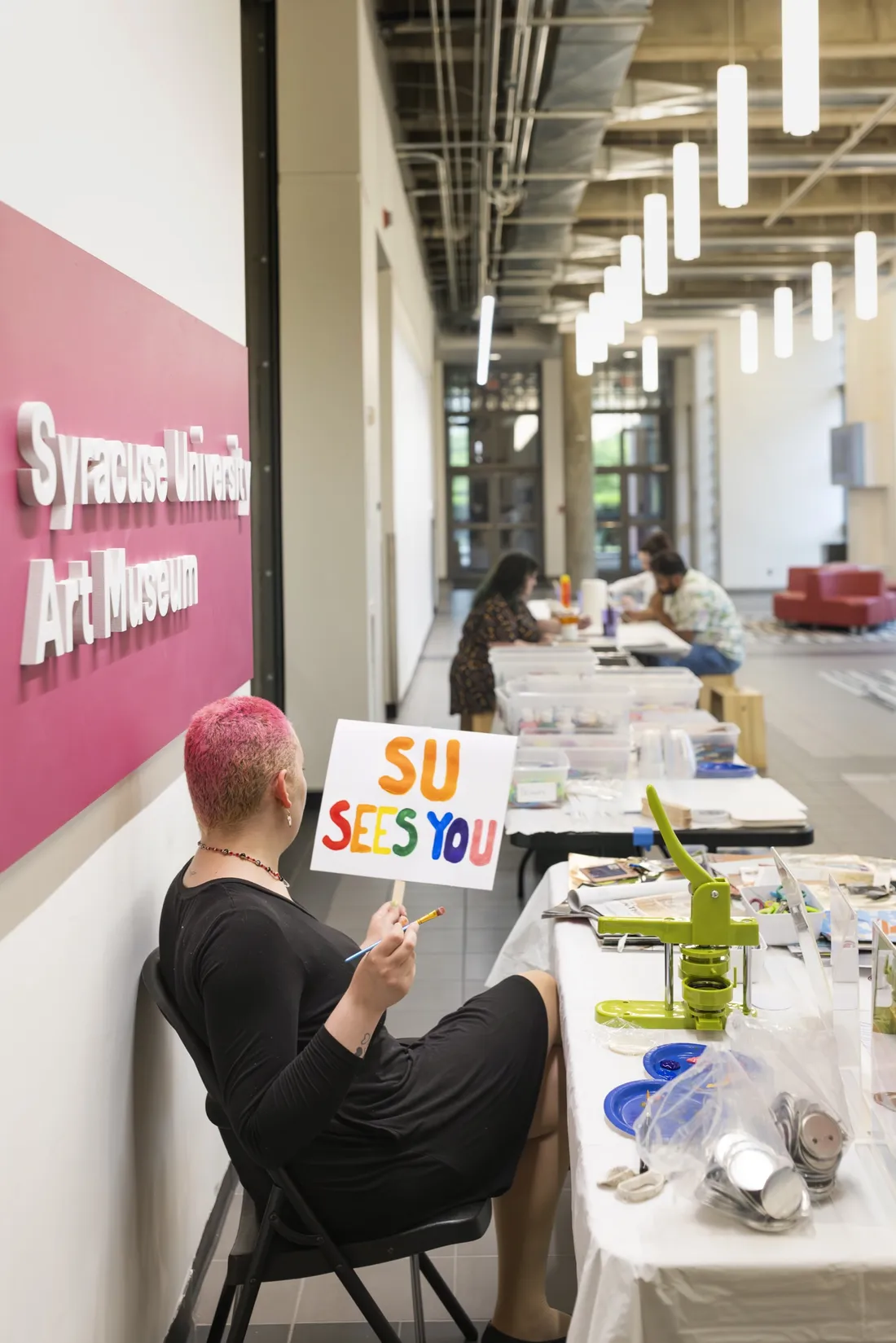 Zia Jackson '20 holding a sign painted with the words "SU Sees You" for the CNY Pride Parade.
