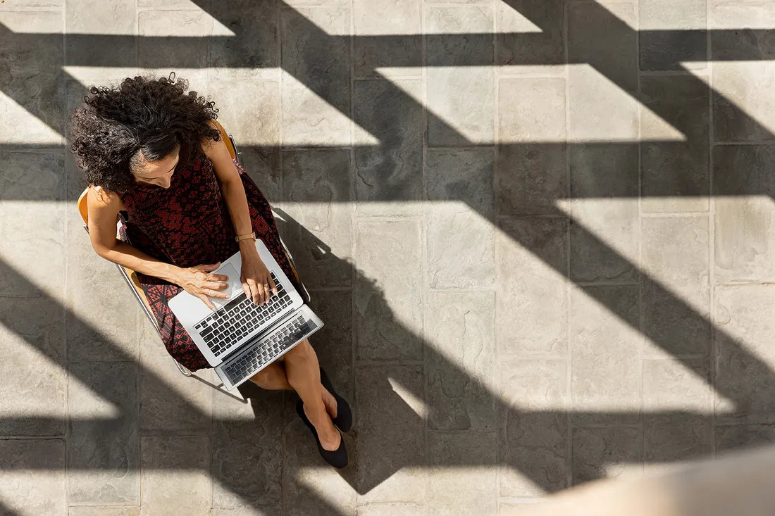 Chanelle Benz works on laptop in courtyard.