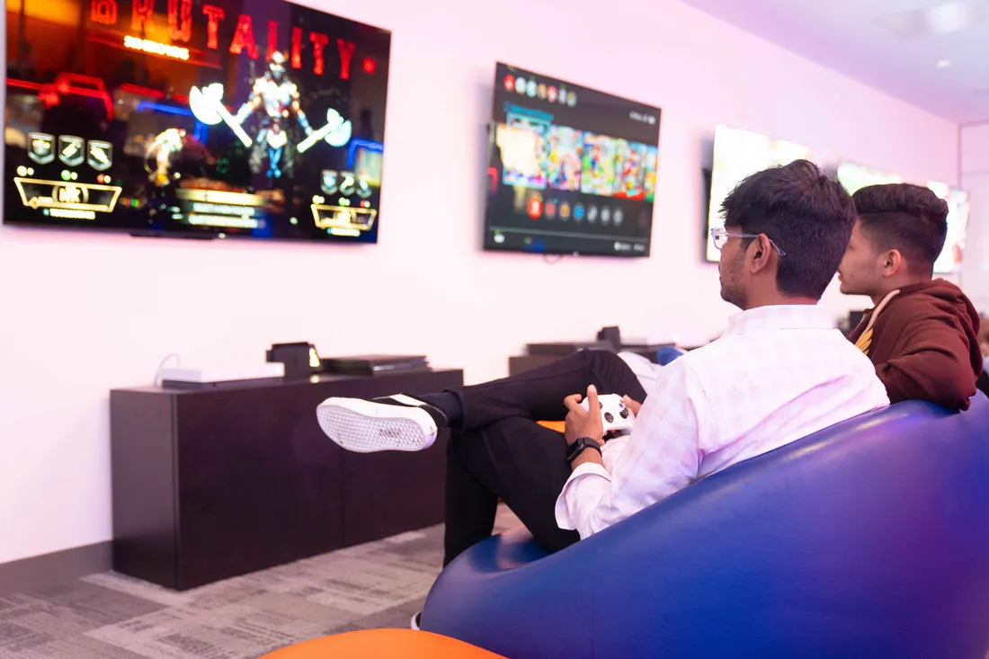 Two students in Esports room playing game on television.