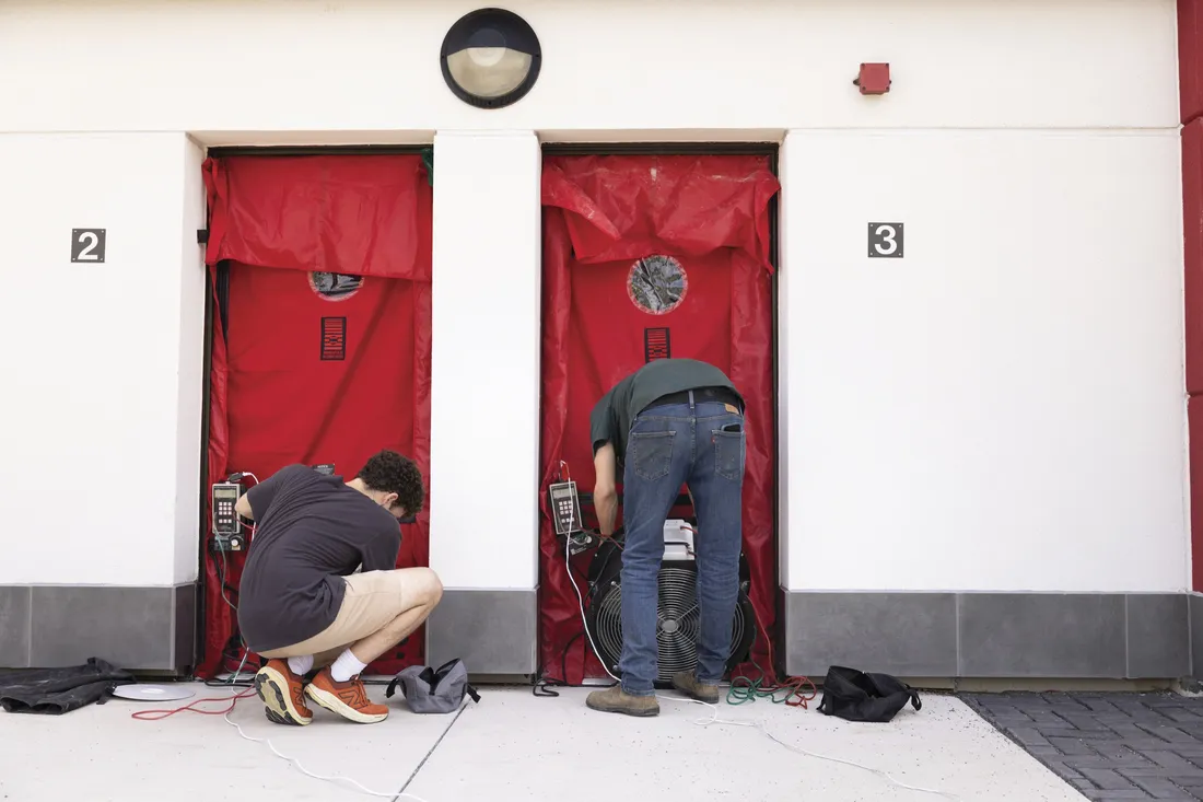Two people working on Syracuse University's South Campus retrofit project standing in front of two apartment doors.