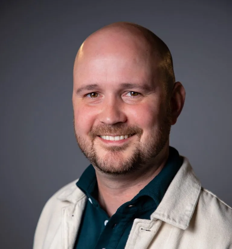 Kieran Lyons smiling in a white jacket.
