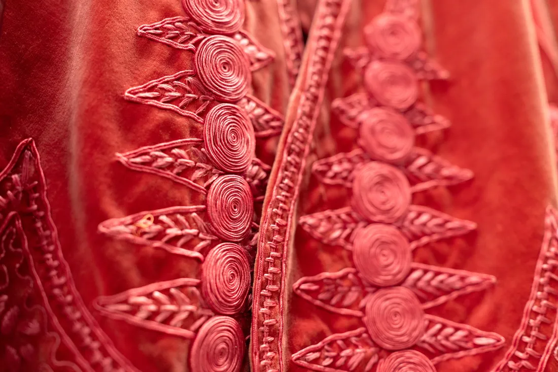 Close up of a red clothing garment with circular and leaf-like designs.