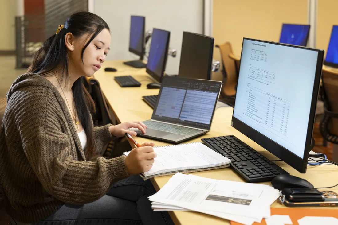 Person sitting in front of computer taking notes.