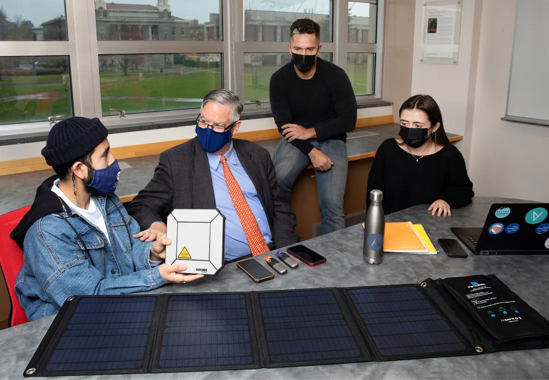 View of Professor Lee McKnight talking with three students at worktable.