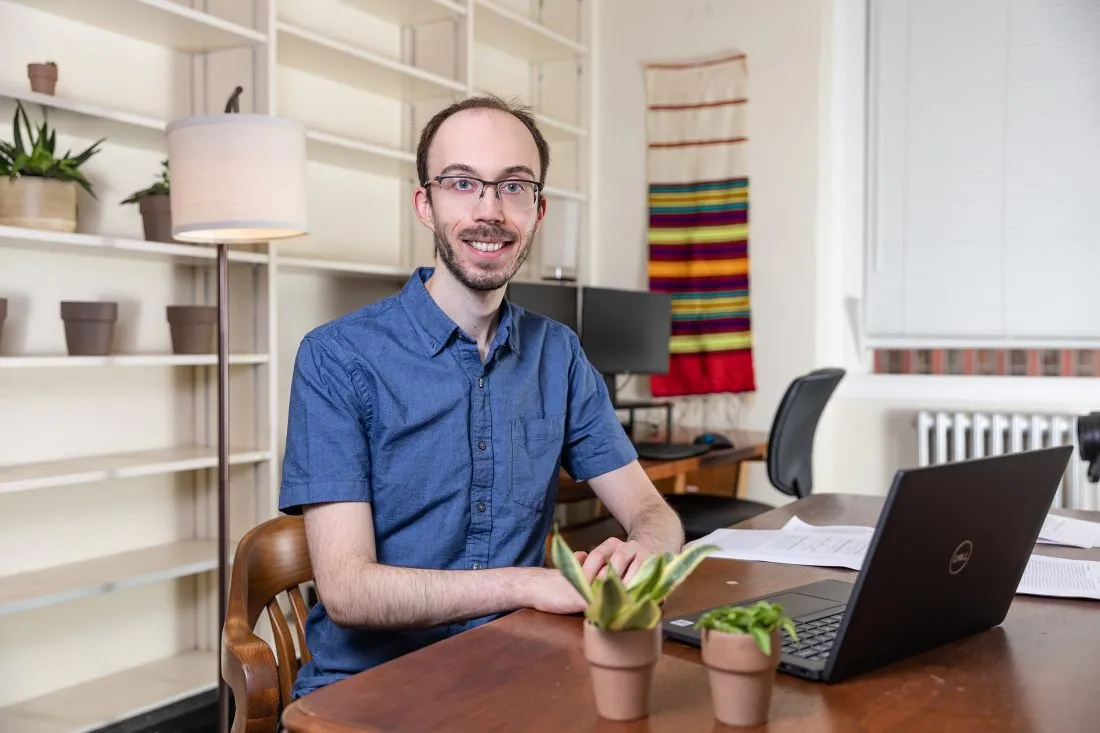Person sits at a desk with a laptop in their home office.