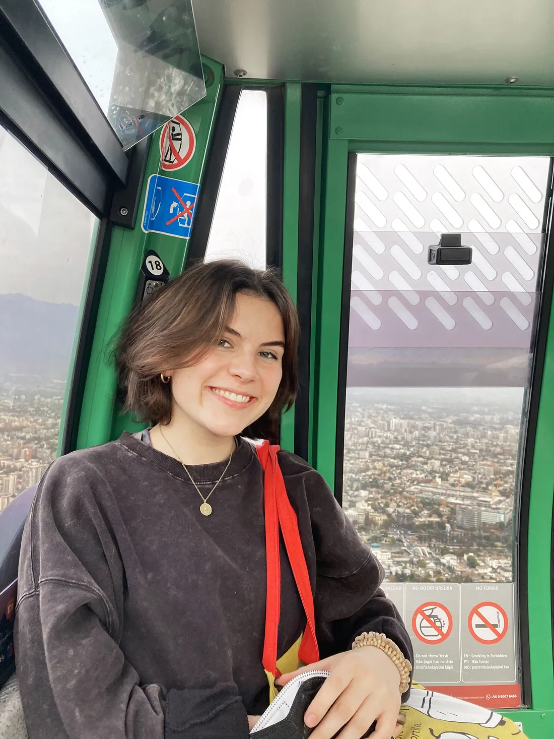 Sophie Clinton poses for a photo inside of a cable car that is in motion up a mountain.