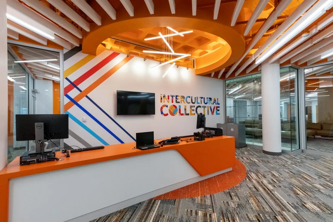 Schine Student Center lobby desk in front of wall that has Intercultural Collective written on it.