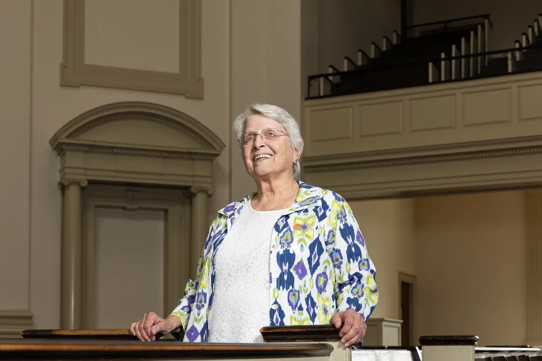 Person standing and smiling while looking into the distance.