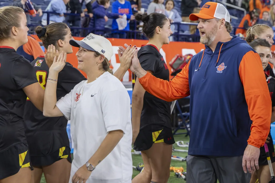 Regy Thorpe and the Syracuse University women's lacrosse team giving high-fives at the end of a game.