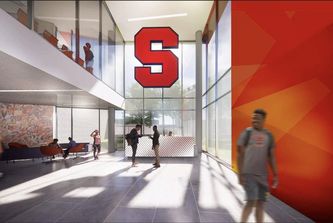 Students walk inside sunny atrium with large Syracuse University block S hanging in window.