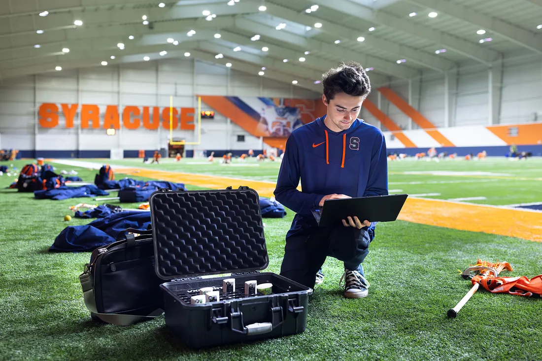 Ryan Severe on a computer setting up GPS equipment for his Sport Analytics class.