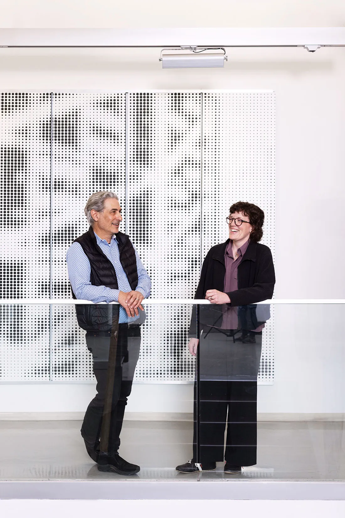 Two professors stand at railing having a conversation.