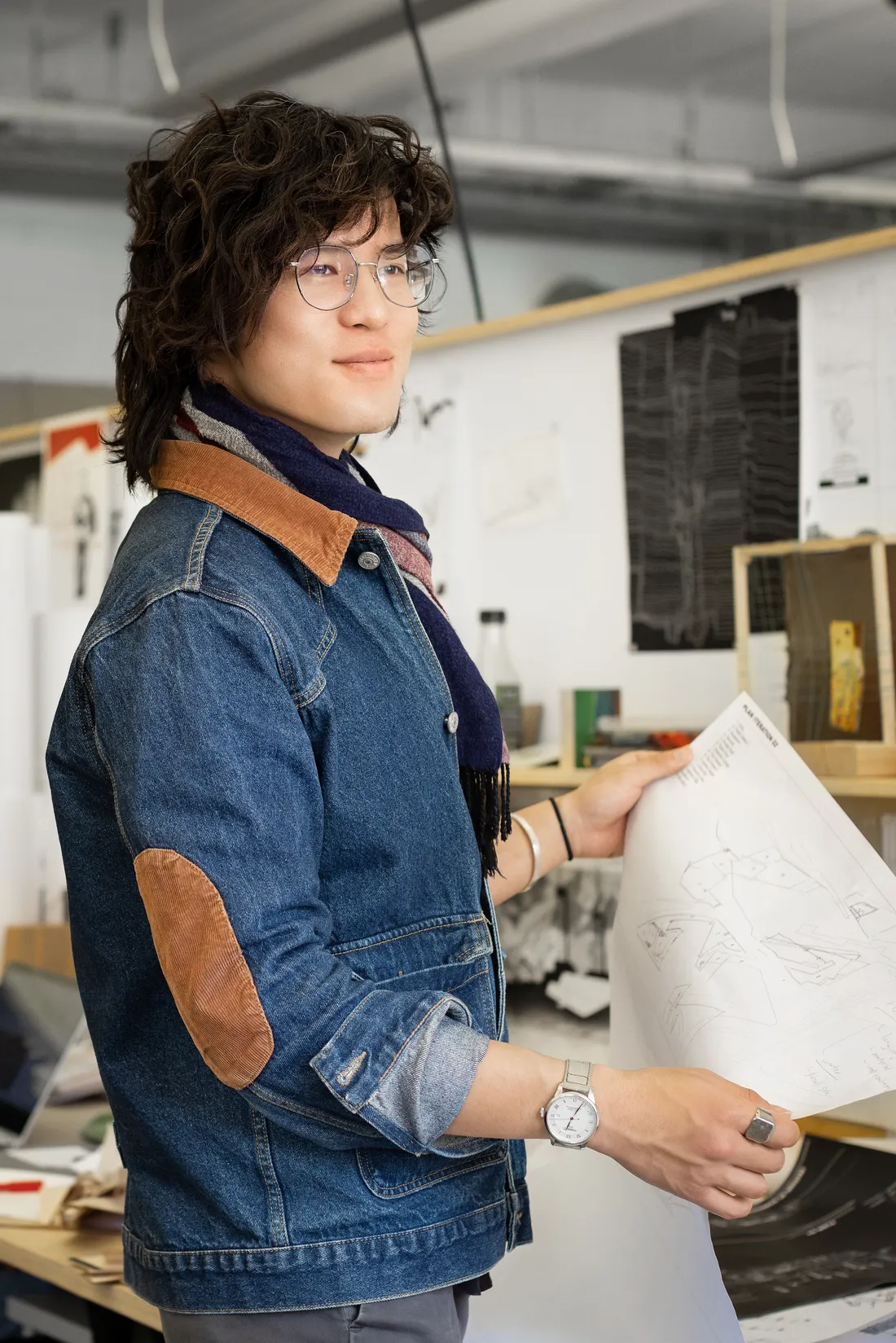 Portrait of Li holding up mockups for a design project.