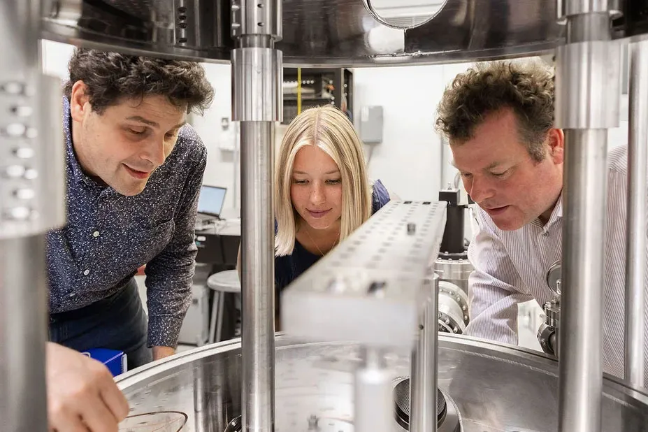 Three scientists look at microscope.