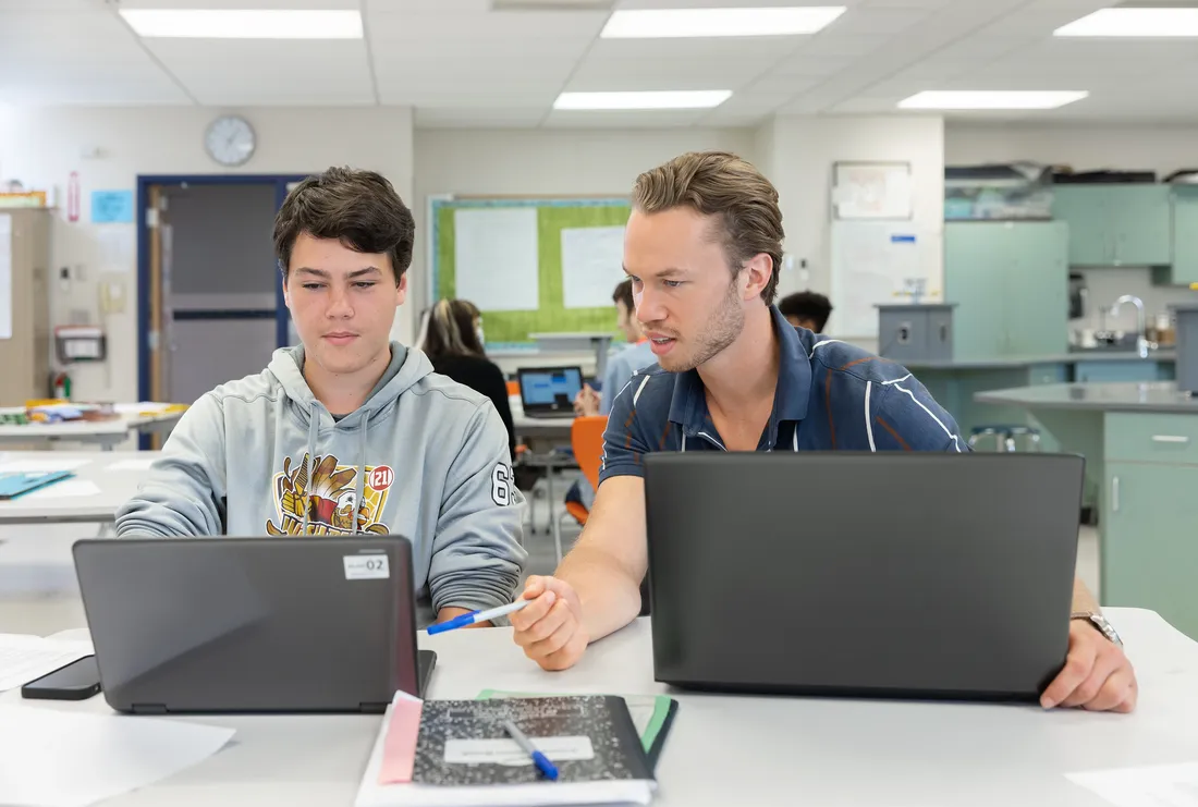Aspiring teacher helping student on computer.