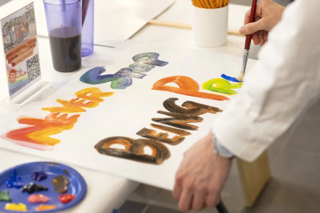 A sign being painted with the words "Never stop being proud."