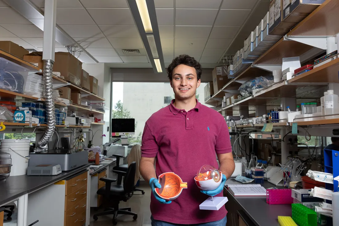 Michael Geiss poses in lab with large model of eyeball.