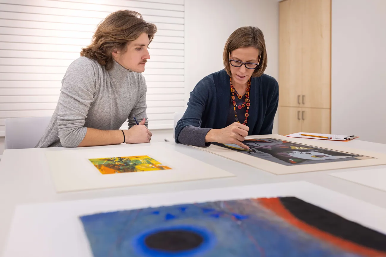 Professor Sascha Scott looking at art with a student.