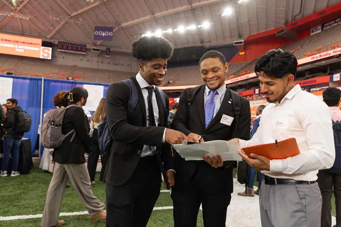 Students looking at papers at a career fair.