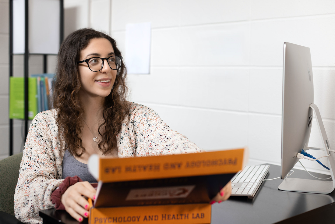 Student Veronica Bucci sits at her desk opening up a lab package.