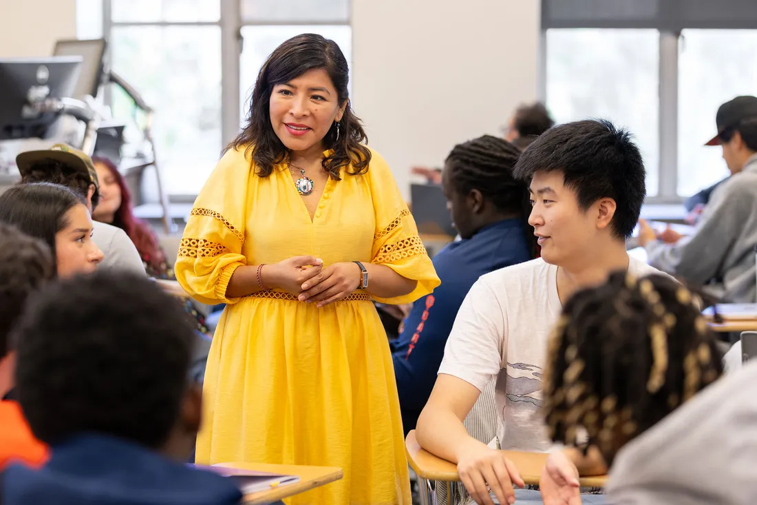 Teachers speaking to students in a classroom.