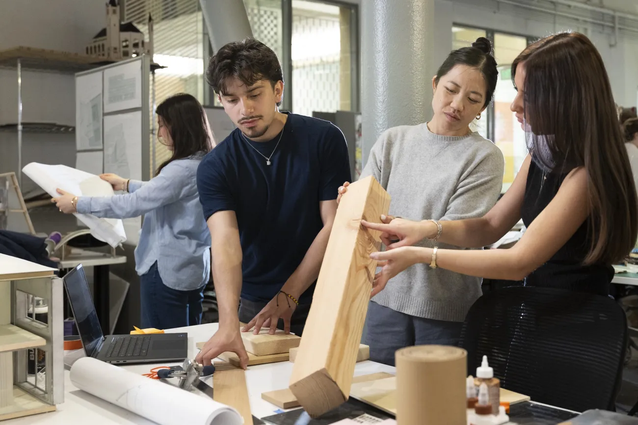 Tiffany Xu holding up a piece of wood to teach architecture students the significance of different materials in construction.