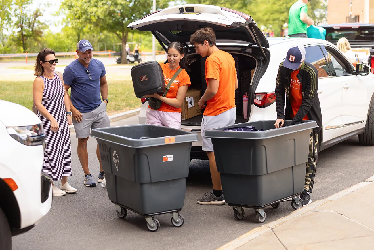 People moving bins out of a van.