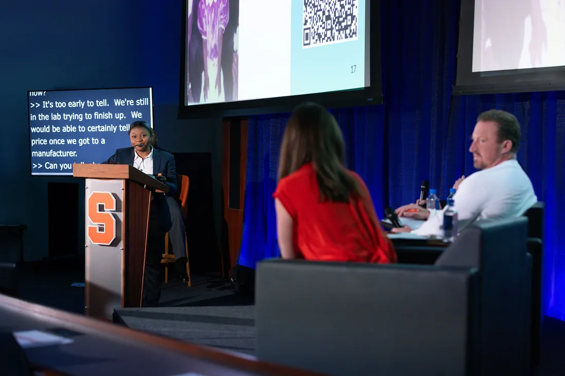 Tosin Alabi on a stage presenting at the Whitman School of Management Orange Tank competition.