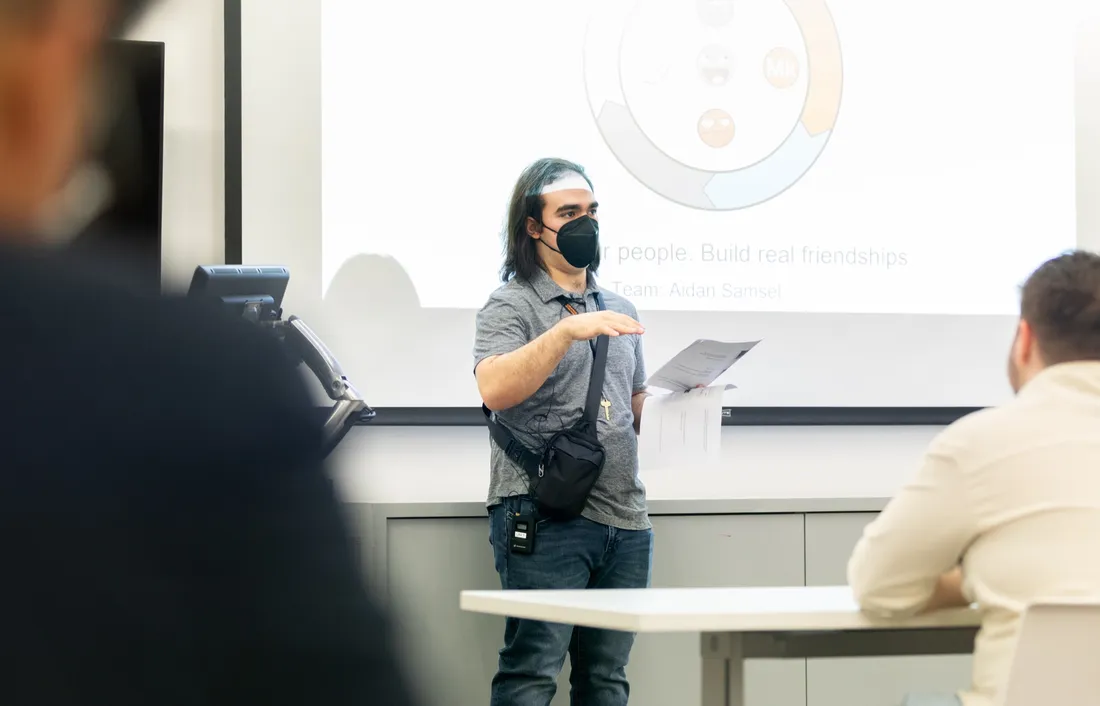 Student Aidan Samsel standing at the front of a room giving a presentation.